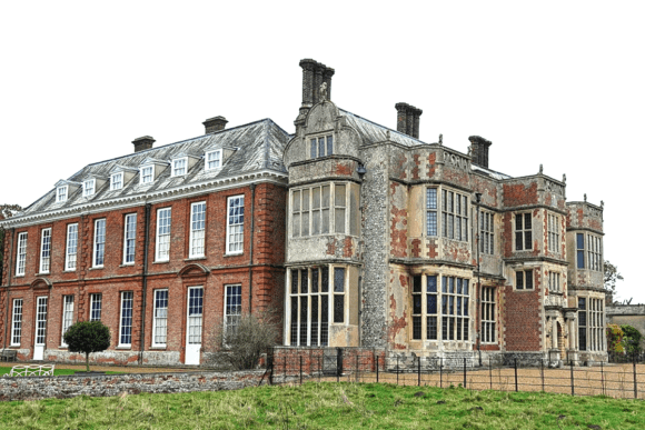 Felbrigg Hall, a large red-brick and stone country house with tall windows and decorative gables, set within landscaped grounds.