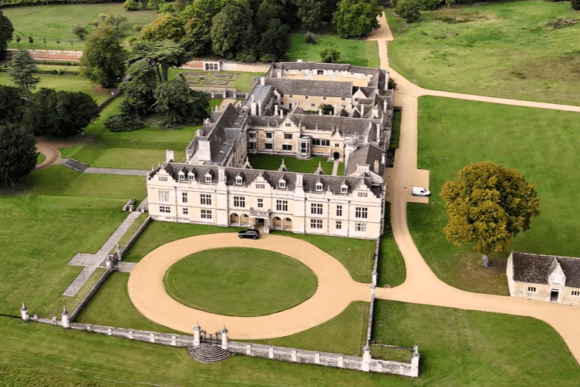 Aerial view of Apethorpe Palace showing the grand historic mansion, courtyard, landscaped gardens, and surrounding parkland.