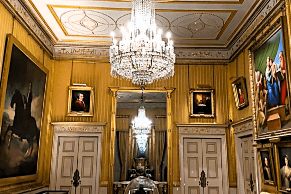 Ornate gilded interior room in Apsley House with chandeliers and classical paintings.