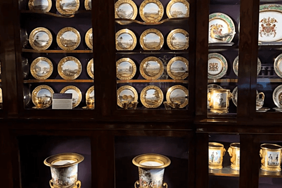 Display cabinet of gilded porcelain plates and cups at Apsley House.