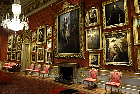 Grand portrait gallery room with red walls, chandeliers, and gilded paintings at Apsley House.
