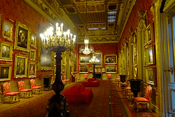 Lavish Picture Gallery at Apsley House with chandeliers, red walls, and gilded framed paintings.