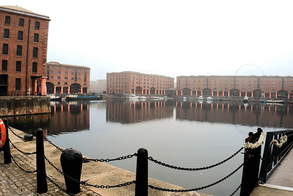 Waterfront view of Royal Albert Dock Liverpool with historic red-brick warehouses reflected in the water.