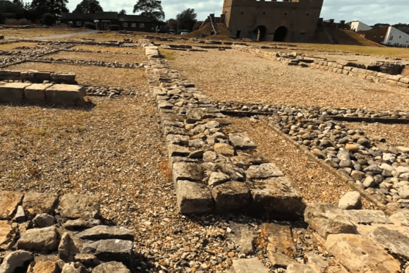 Stone foundation remains at Arbeia Roman Fort with reconstructed West Gate in the background, South Shields