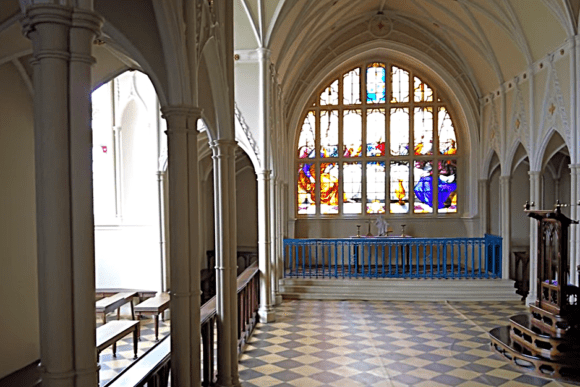 Gothic-style chapel interior at Audley End House with stained glass window and vaulted arches in Essex