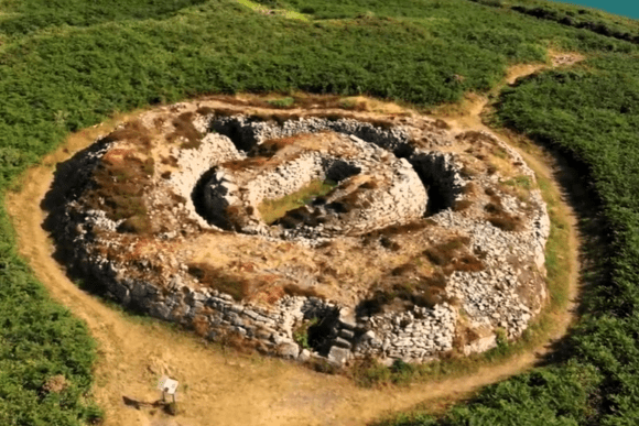 Aerial view of Ballowall Barrow Bronze Age burial cairn with concentric stone walls in Cornwall, England