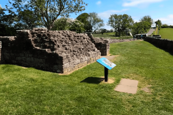 Stone remains of Banks East Turret on Hadrian’s Wall with information sign and grassy setting in Northumberland