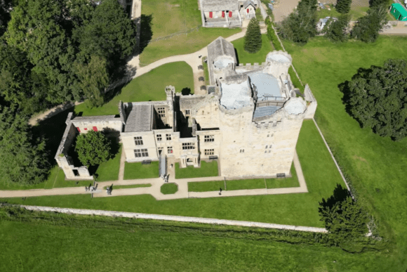 Top-down aerial view of Belsay Castle with stone towers and surrounding lawns