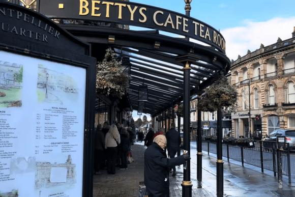 Entrance to Bettys Café Tea Rooms in Harrogate with its iconic black canopy, elegant signage and visitors waiting outside the famous Yorkshire tea room.