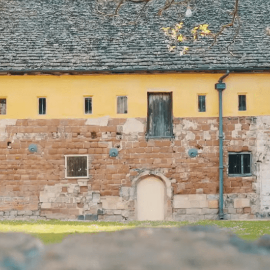 Blackfriars Priory in Gloucester showing medieval stone walls, narrow arched doorway, and tiled monastic roof