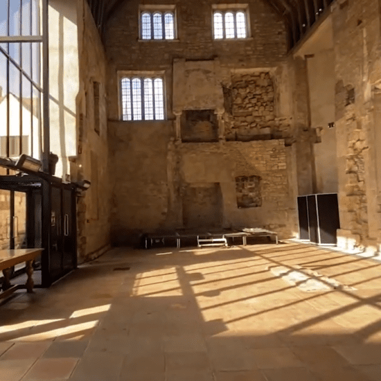 Interior of Blackfriars Priory in Gloucester showing tall medieval walls, timber-framed window light, and stone arches