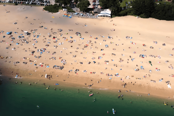 Aerial view of Blackpool Sands in Devon filled with beachgoers enjoying the golden shoreline, clear turquoise water, and one of South Devon’s most popular family-friendly beaches.
