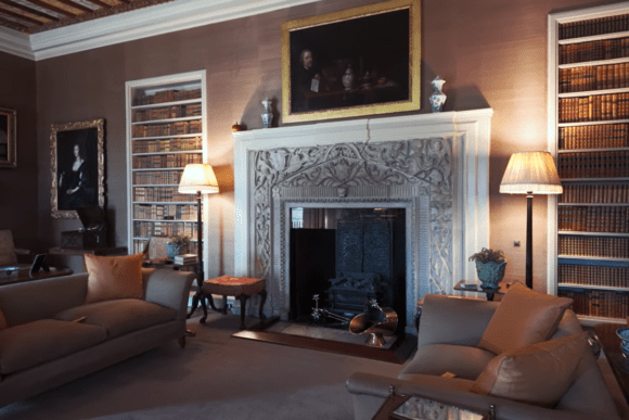 Jacobean-era historic interior room at Blackfriars Priory, Gloucester, featuring carved stone fireplace, period portraits, and floor-to-ceiling bookshelves