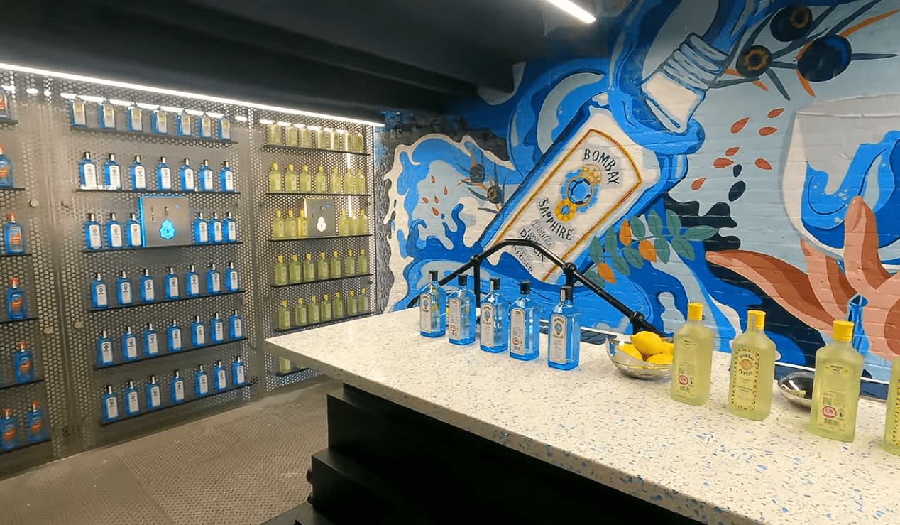 Bombay Sapphire Distillery gin display featuring Bombay Sapphire bottles, flavoured gin collection, tasting counter, and colourful botanical mural in Hampshire, England.