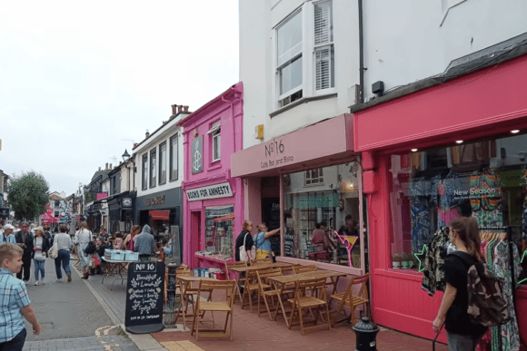 Colourful independent shops, cafés and pedestrians along a busy street in Brighton’s North Laine, one of the city’s popular shopping districts.