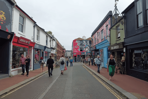 Colourful independent shops, street art and visitors along a lively street in Brighton’s North Laine shopping district.