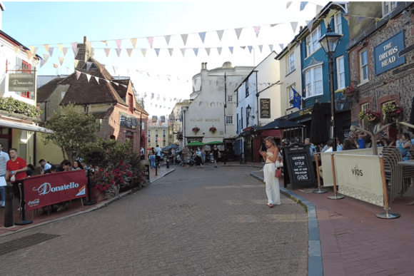 Historic street in Brighton’s The Lanes with colourful buildings, restaurants, traditional pubs, outdoor seating and visitors.