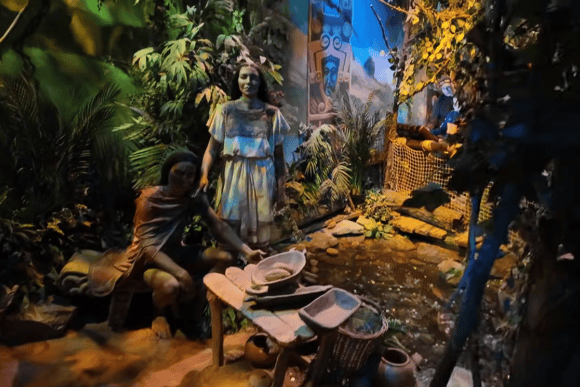 Rainforest-themed chocolate history exhibit at Cadbury World featuring figures in a tropical setting surrounded by lush plants and traditional tools.