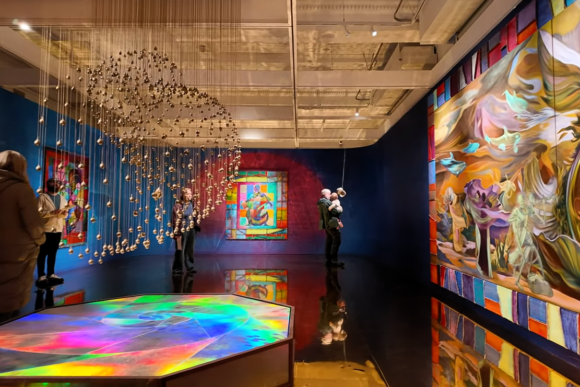 Contemporary art exhibition at Cartwright Hall Art Gallery featuring large colourful paintings, immersive installation art, suspended sculptural elements, and visitors exploring a vibrant gallery space in Bradford.