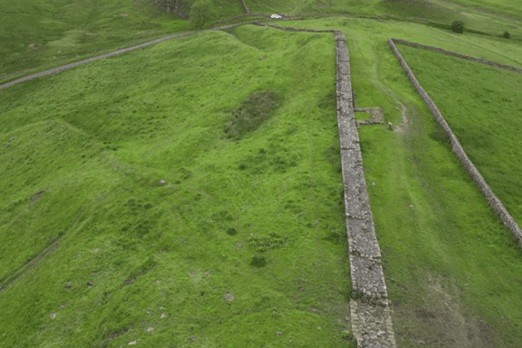 Aerial view of Cawfields Roman Wall stretching across green hills, with parallel earthworks and paths marking Hadrian’s Wall.