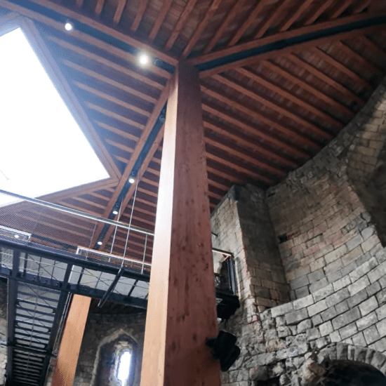 Interior of Clifford's Tower in York showing stone walls, timber roof, and modern walkway.
