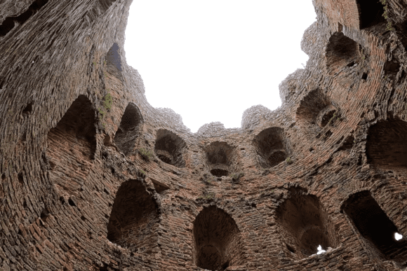 Interior view looking up inside Cow Tower, Norwich, showing curved brick walls with arched recesses and openings.