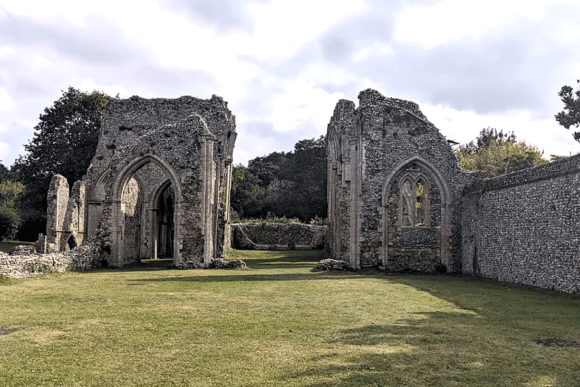 Ruins of Creake Abbey showing stone archways and walls standing in a grassy courtyard.