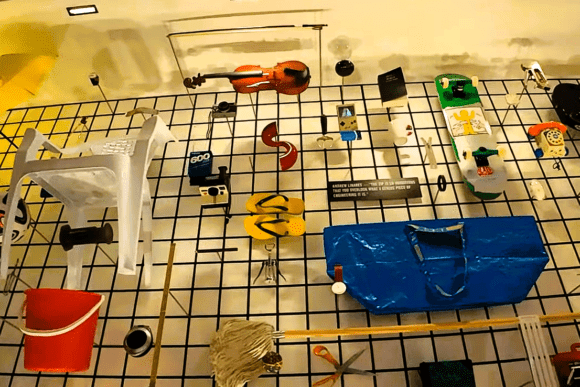 Creative product design exhibition at the Design Museum in London featuring everyday objects, furniture, consumer products, and innovative industrial design pieces displayed on a suspended grid installation.