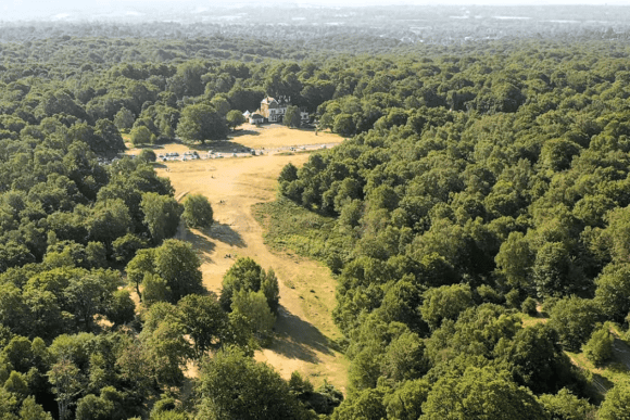 Aerial view of Epping Forest at High Beach, Essex, featuring ancient woodland, open heathland, and High Beach Visitor Centre surrounded by dense forest.
