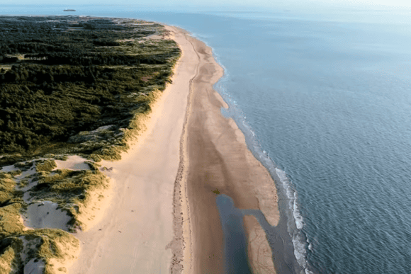 Aerial view of Formby Beach featuring expansive golden sands, rolling sand dunes, coastal pine woodland, and the Irish Sea along England's scenic Sefton coastline.