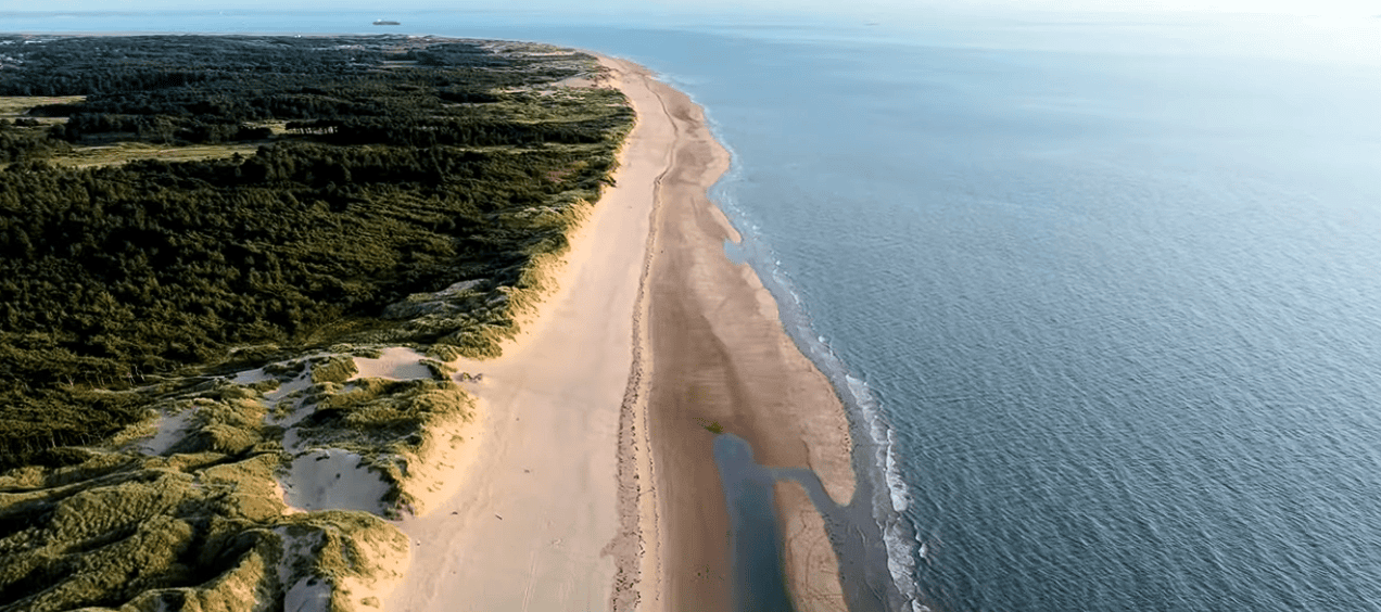 Aerial view of Formby Beach featuring expansive golden sands, rolling sand dunes, coastal pine woodland, and the Irish Sea along England's scenic Sefton coastline.