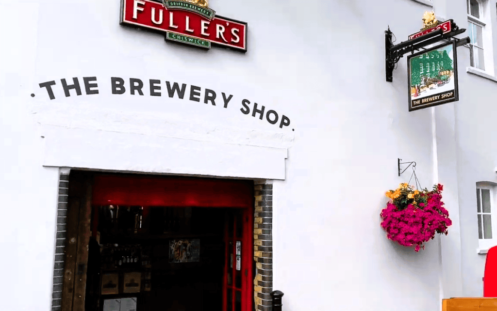 Fuller's Griffin Brewery Shop entrance in Chiswick, London, featuring the iconic Fuller's sign, brewery shop entrance, and hanging flower basket.