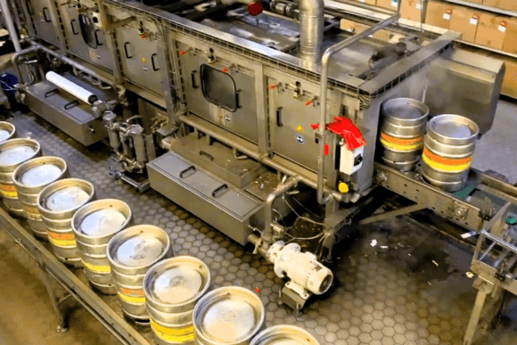 Beer kegs moving along an automated production line at Fuller's Griffin Brewery in Chiswick, showcasing the brewery's modern keg filling and packaging process.