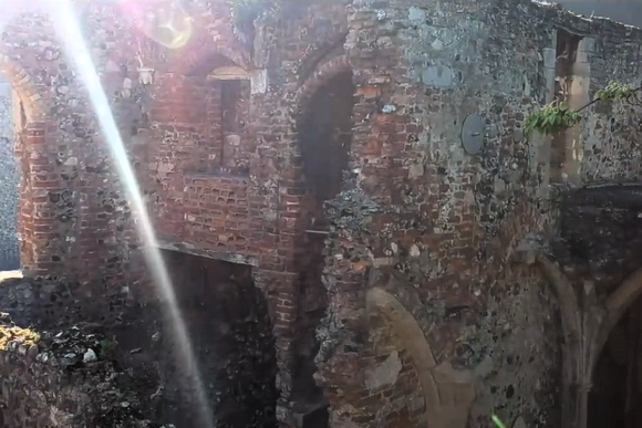 Ruins of Greyfriars’ Cloisters in Great Yarmouth with weathered brick arches and sunlight streaming through the historic structure.