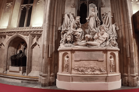 Large marble monument inside Guildhall London featuring classical sculpted figures set against Gothic stone arches.