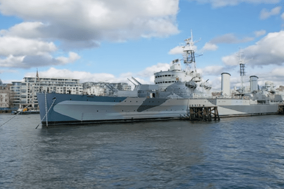 HMS Belfast warship moored on the River Thames near Tower Bridge in London.