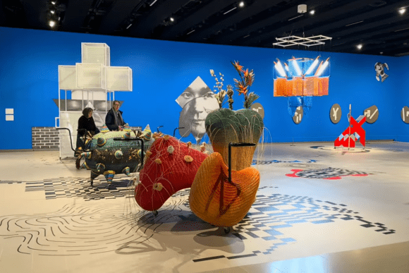 Visitors explore a vibrant contemporary art exhibition at Hayward Gallery in London, featuring large-scale colourful sculptures, immersive installations, graphic floor designs, and bold blue gallery walls.