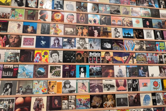 Wall display of hundreds of colourful vintage and contemporary vinyl record album covers at Hayward Gallery in London, showcasing iconic music artwork and popular album designs.