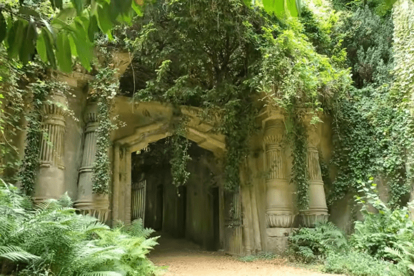 Ivy-covered stone entrance and Gothic archway surrounded by greenery at Highgate Cemetery.