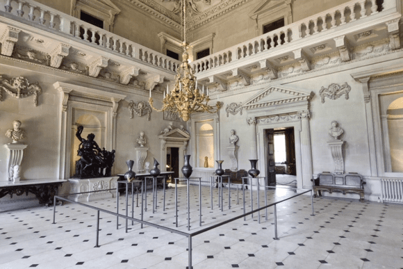 Grand marble hall interior at Houghton Hall with chandelier, sculptures, and classical architecture.