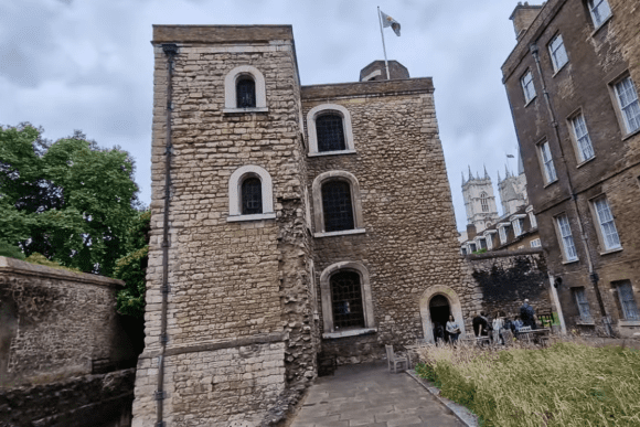 Medieval stone Jewel Tower in Westminster, London, with visitors standing near the entrance.