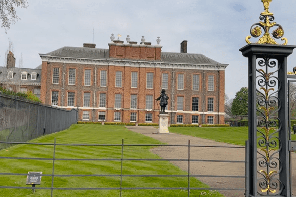 Kensington Palace in London with a statue of King William III standing in the gardens in front.