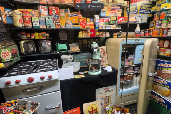 Vintage kitchen display at the Museum of Brands in London featuring a retro refrigerator, classic cooker, household appliances, and iconic food packaging from mid-20th-century Britain.