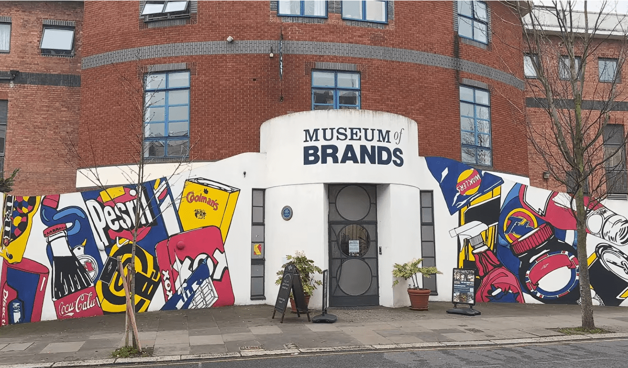 Exterior entrance of the Museum of Brands in London, featuring a colourful pop-art mural with iconic consumer product imagery surrounding the museum’s main doorway.