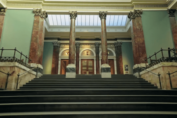 Grand interior staircase of the National Gallery with marble columns and ornate classical architecture.