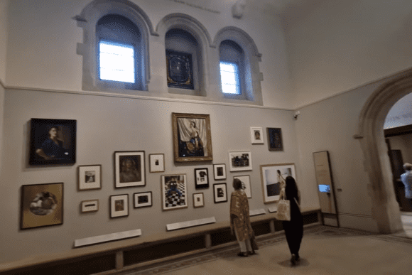 Interior gallery at the National Portrait Gallery with visitors viewing framed portraits on a wall.