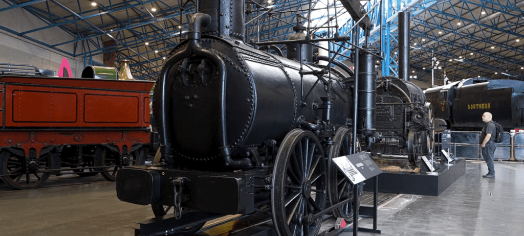 Historic black steam locomotive displayed inside the National Railway Museum in York, showcasing early railway engineering and Britain's industrial heritage.