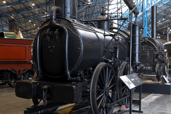 Historic black steam locomotive displayed inside the National Railway Museum in York, showcasing early railway engineering and Britain's industrial heritage.