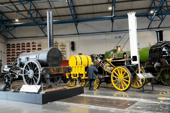 Historic steam locomotives and early railway vehicles displayed inside the National Railway Museum in York, showcasing the evolution of Britain's railway engineering and transport history.