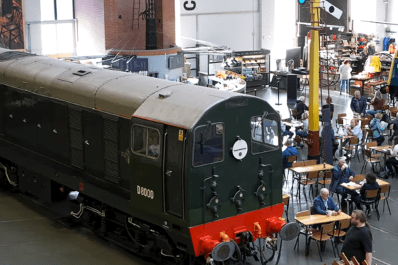 Historic British Rail diesel locomotive D8000 displayed inside the National Railway Museum in York, surrounded by visitors exploring railway heritage exhibits.